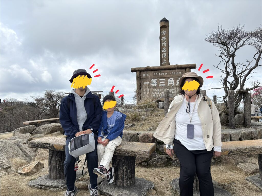 御在所岳の山頂で記念撮影をする小2の息子と親